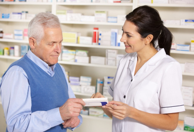 american pharmacist serving a senior man in pharmacy
